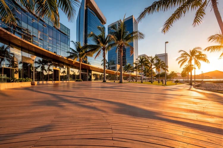 Pessoas caminhando em uma orla moderna com palmeiras e edifícios ao fundo na Barra Sul, Balneário Camboriú.