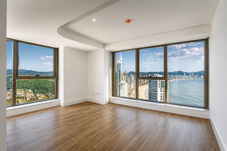 Ambiente sem mobília em unidade duplex do Yachthouse, com janelões voltados para a serra e para a orla de Balneário Camboriú.